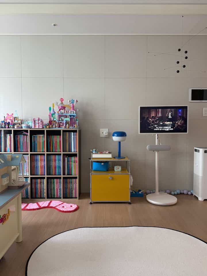 白とナチュラルカラーの子供部屋、書棚やおもちゃ、テレビが配置された雰囲気のあるインテリア
