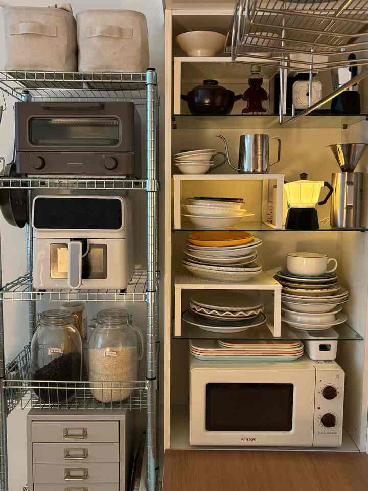 ベージュと白の色調のキッチンスペース、整然と並べられた棚に様々な食器やキッチン家電が配置されたミニマルな雰囲気のインテリア