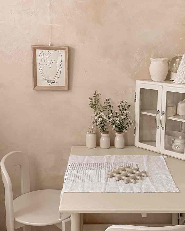 柔らかなベージュ色調のダイニングルーム、ベージュのダイニングテーブルと椅子、花瓶が配置された清潔感のある空間