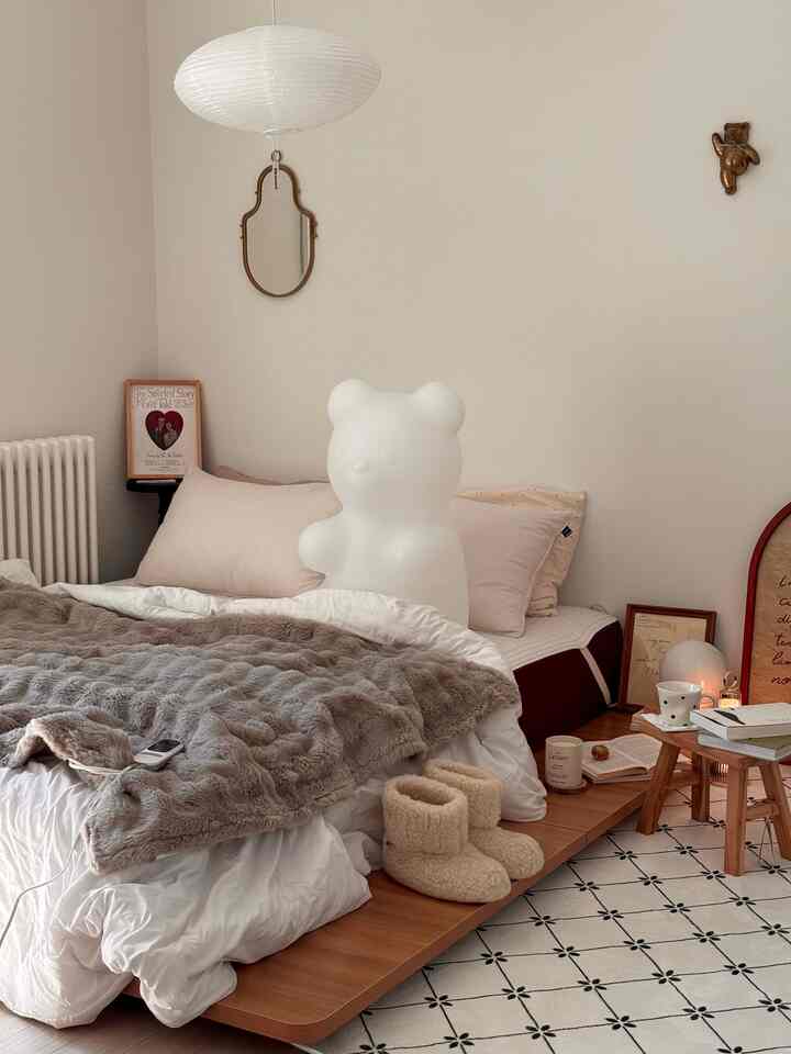 アイボリーとベージュ色調の寝室、クマ型ランプと柔らかなブランケットが配置された雰囲気のあるインテリア
