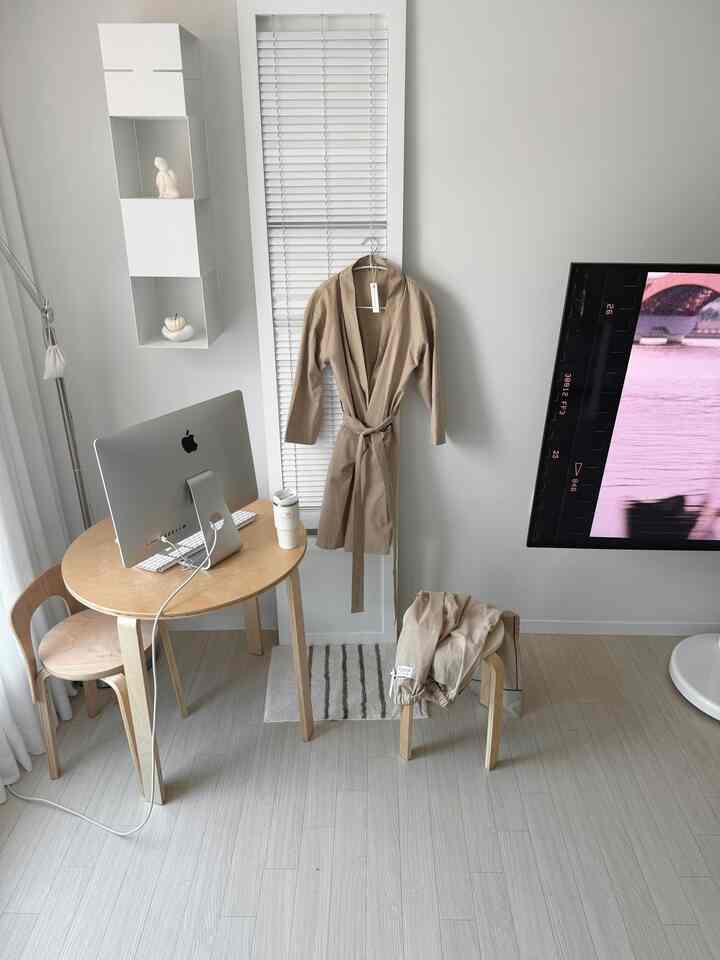 明るい木目調とベージュのホームウェアが配置されたコンパクトでモダンなワンルームのホームオフィス空間