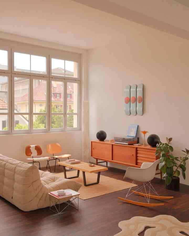 A cozy mid-century modern living room with warm wood tones and beige hues, featuring a sofa, armchair, and wooden bench