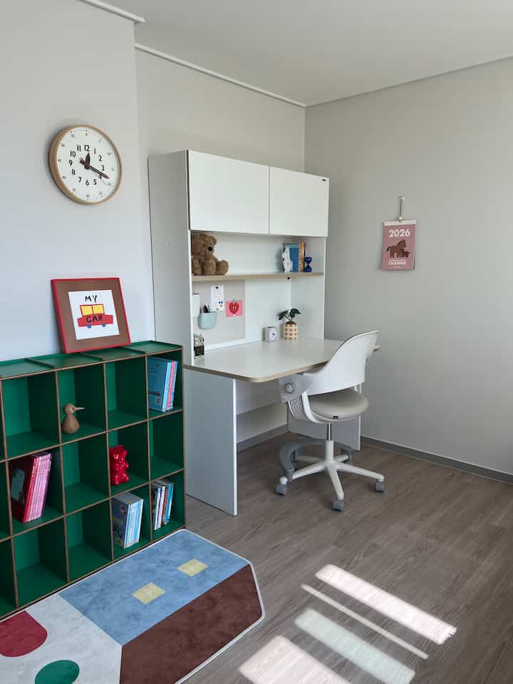 白と緑の色調の子供部屋、デスクや本棚、子供向けの小物が配置された清潔感ある居心地の良いインテリア