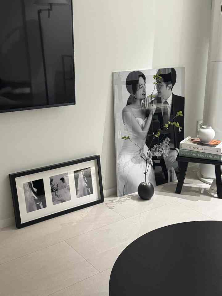 白と黒のトーンで構成されたリビング、床と壁に置かれた黒い額縁と感情的な白黒の結婚写真が配されたシンプルなインテリア