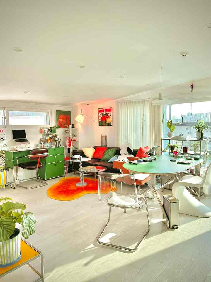 白を基調としたミッドセンチュリーモダンのリビング、グリーンの家具と植物が調和したホームオフィス兼ホームカフェの印象的な空間