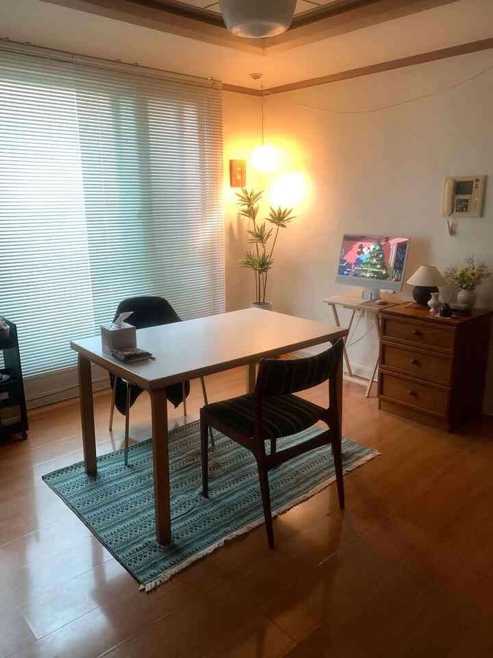 白と木の調和が取れた狭い部屋にホームオフィスとダイニングテーブルが配置された印象的な空間