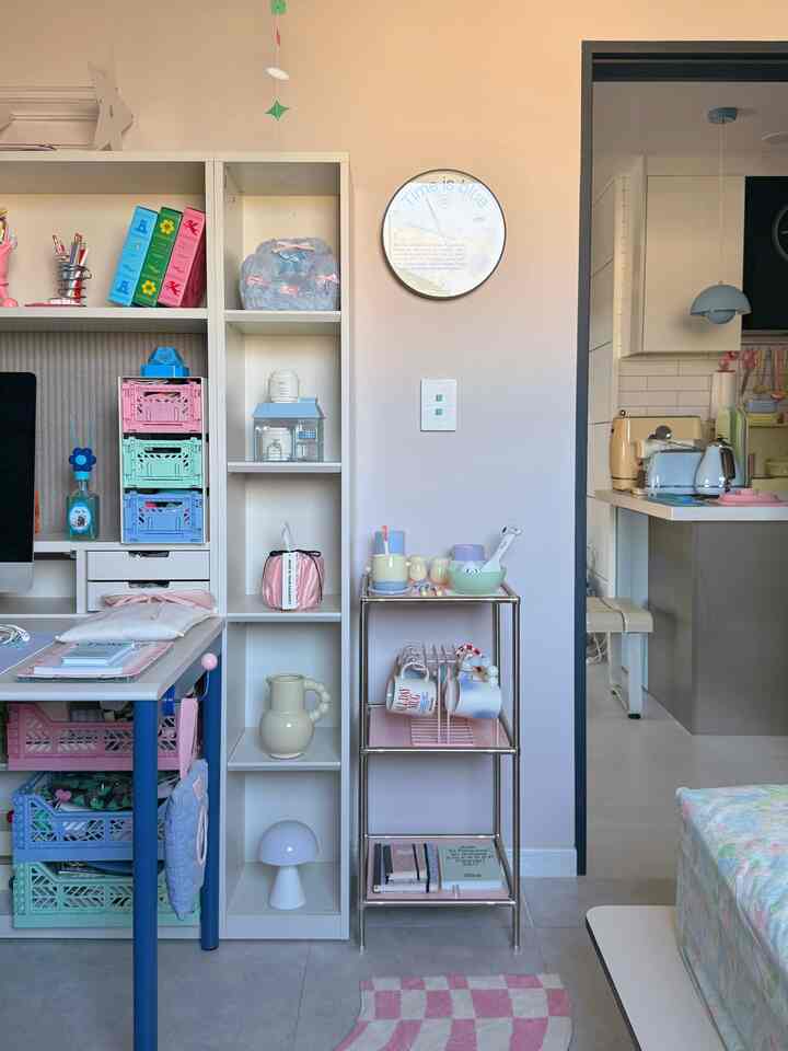 柔らかなピンク色の壁とホワイトの棚、小物が配置されたコンパクトな空間