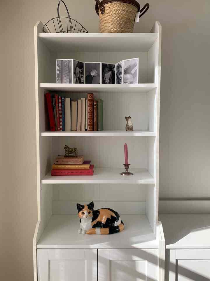 ホワイトとベージュの明るい空間、白い本棚とミニマルな装飾が配置された清潔感のあるインテリア