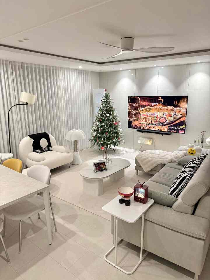 白を基調としたリビング、クリスマスツリーとマルティネッリルーチェのテーブルランプが配置されたモダンなインテリア