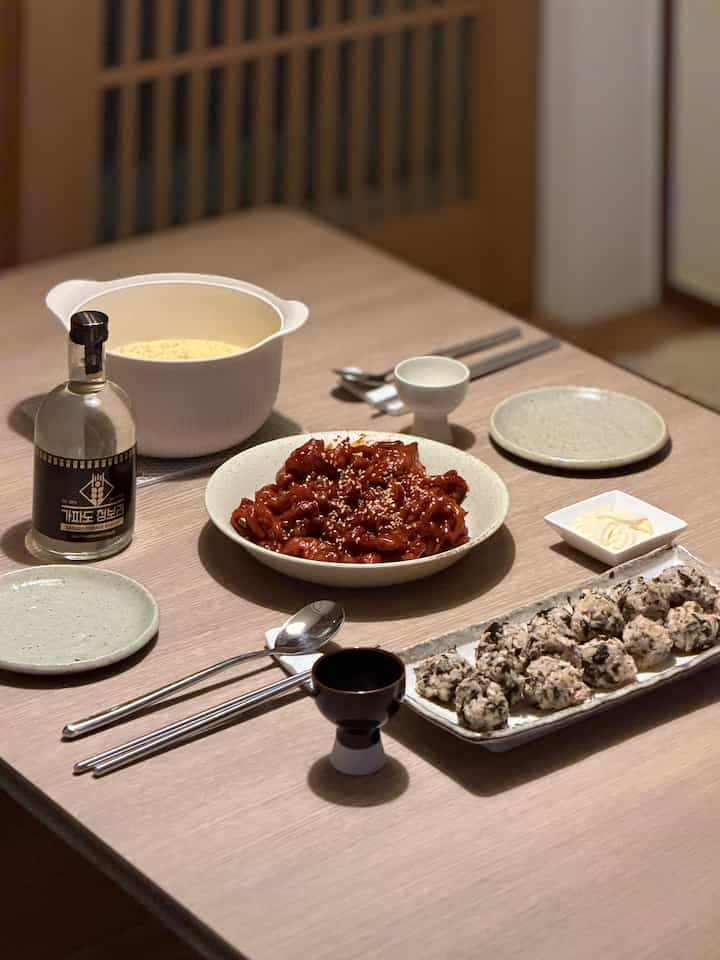ベージュ色のダイニングテーブルに韓国料理と酒器、皿が整然と並べられた落ち着いたダイニング空間
