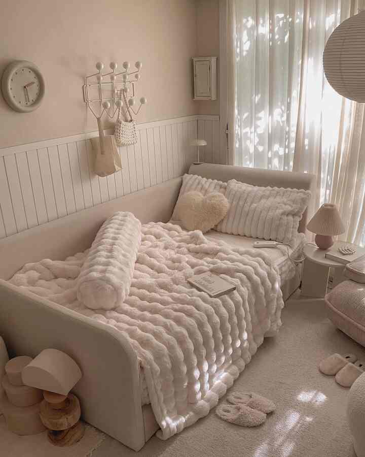 暖かいベージュと白の色調の寝室、かわいらしいソファベッドと柔らかなブランケットが配置されたシンプルでナチュラルなインテリア