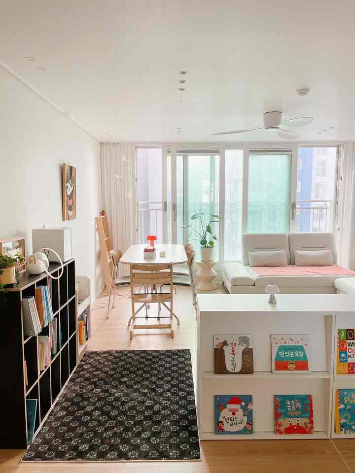 ホワイトと木目調のリビング・ダイニングスペース、子供向け本棚が配置された明るくナチュラルな雰囲気のインテリア