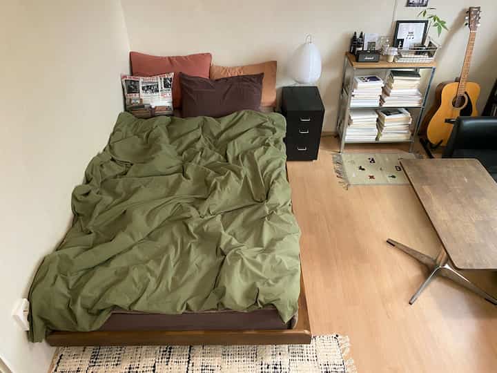 カーキとブラウンのトーンが特徴的なヴィンテージ風寝室、木製家具とステンレスの棚が調和した居心地の良い空間