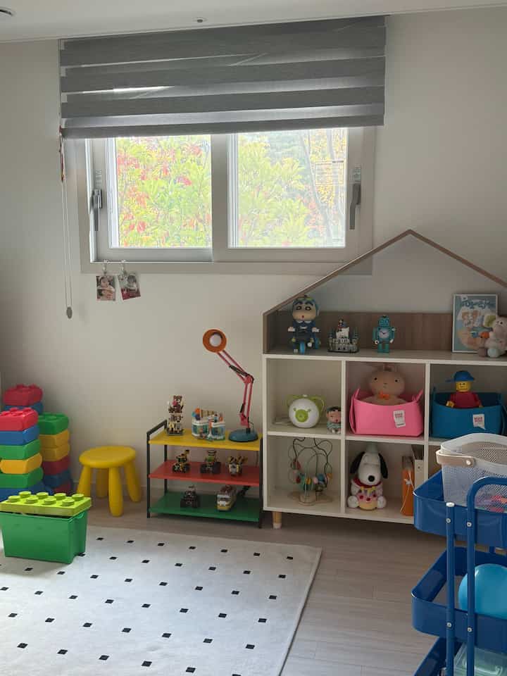 ナチュラルカラーと白を基調とした子供部屋、絵本棚やおもちゃ収納、子供用家具が配置された明るく清潔感のあるインテリア