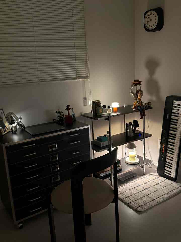 黒と白のトーンの小さなミニマルなホームオフィス、机とチェスト、棚に様々な小物と照明が配置された雰囲気のあるインテリア
