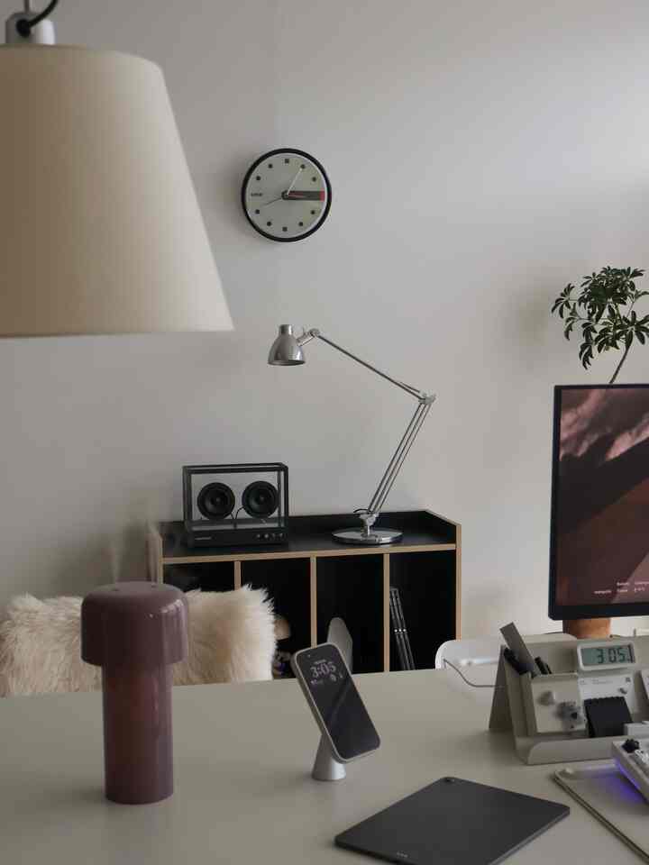 白を基調としたホームオフィス、デスクにモニターや照明、スマートフォンスタンドが整った清潔感のある作業空間