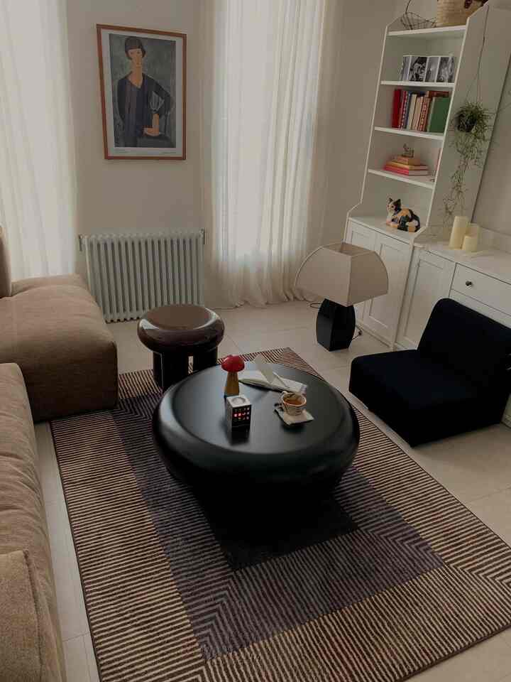 ナチュラルカラーのリビングルーム、ベージュのソファとブラックの円形テーブルが配置された落ち着いた雰囲気のインテリア