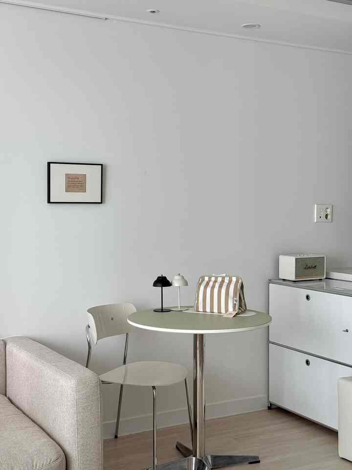 白を基調としたリビング、ベージュのソファとオリーブ色の丸いダイニングテーブルにレザーのランチョンマットが配置された雰囲気のあるモダンなインテリア