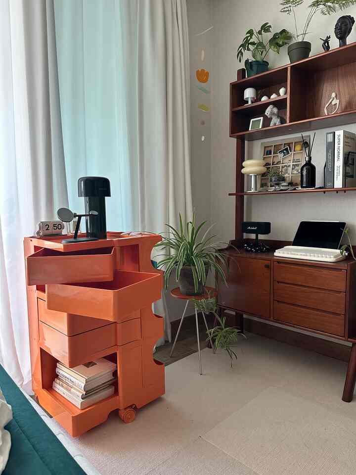 ナチュラルな色調とオレンジの収納が配置された落ち着いたリビングの一角