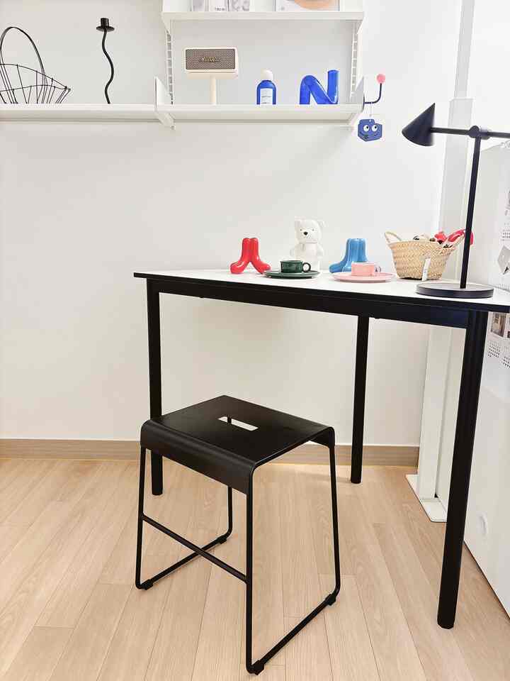 白い壁とテーブル、黒いスツールが配置されたモダンな書斎の雰囲気のあるインテリア