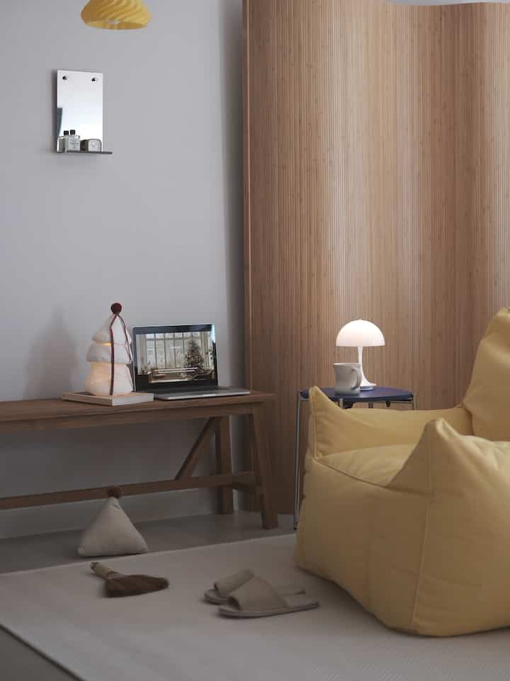 ナチュラルカラーのリビング、黄色のビーズクッションとポータブルライトが配置された落ち着いた空間