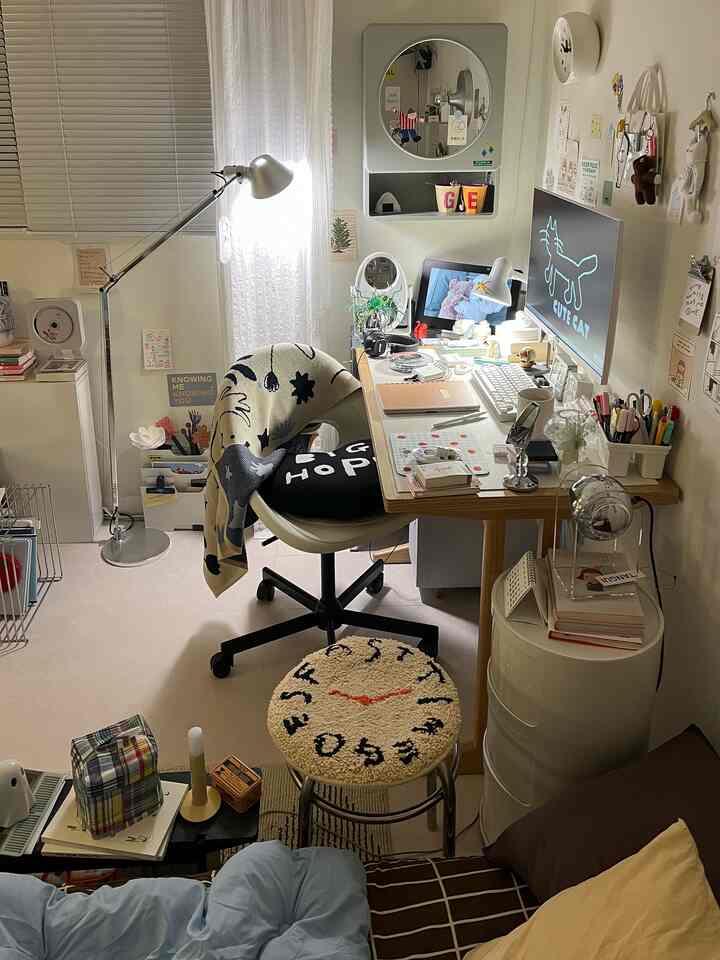 白と木目調が調和した小さなワンルームのホームオフィス、デスクと椅子を中心に壁の装飾と照明で温かみのあるインテリア