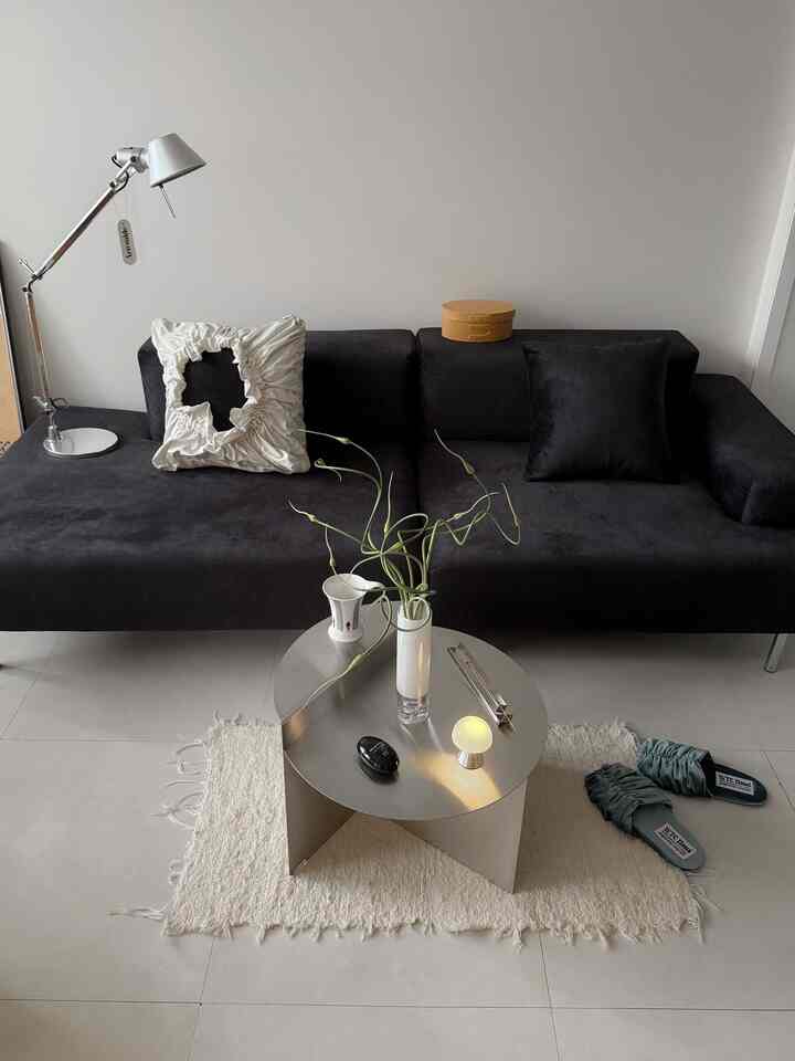 黒のソファとシルバーのステンレス製円形コーヒーテーブルが配置されたモダンでシンプルなリビングルーム