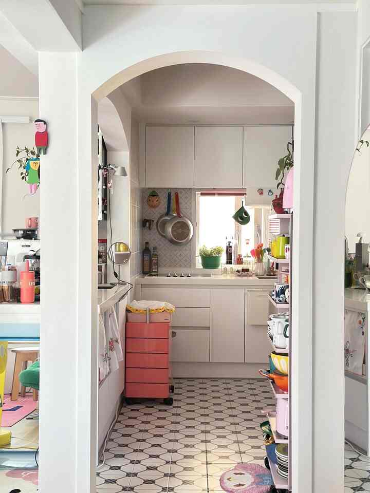 白色の落ち着いたコンパクトなキッチン、アーチ型の入り口と収納キャビネット、IHクッキングヒーターと整頓された調理器具が配置された雰囲気のある空間