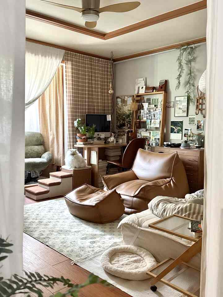 木目調とアイボリーの色調のリビング、レザーの大きなビーズクッション、薄いアイボリーマットレス、デスクと猫が配置された雰囲気のあるコンパクトな空間