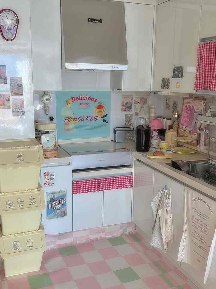 白とピンクの色調のキッチン、チェック柄のカーテンとラグが配置された雰囲気のあるレトロインテリア