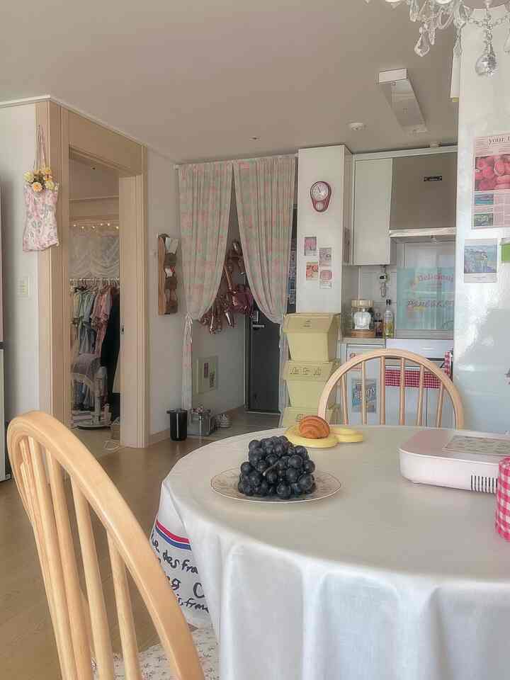 明るいホワイトと木目調が調和したキッチン、白いテーブルクロスとダイニングチェアが配置された雰囲気のあるインテリア