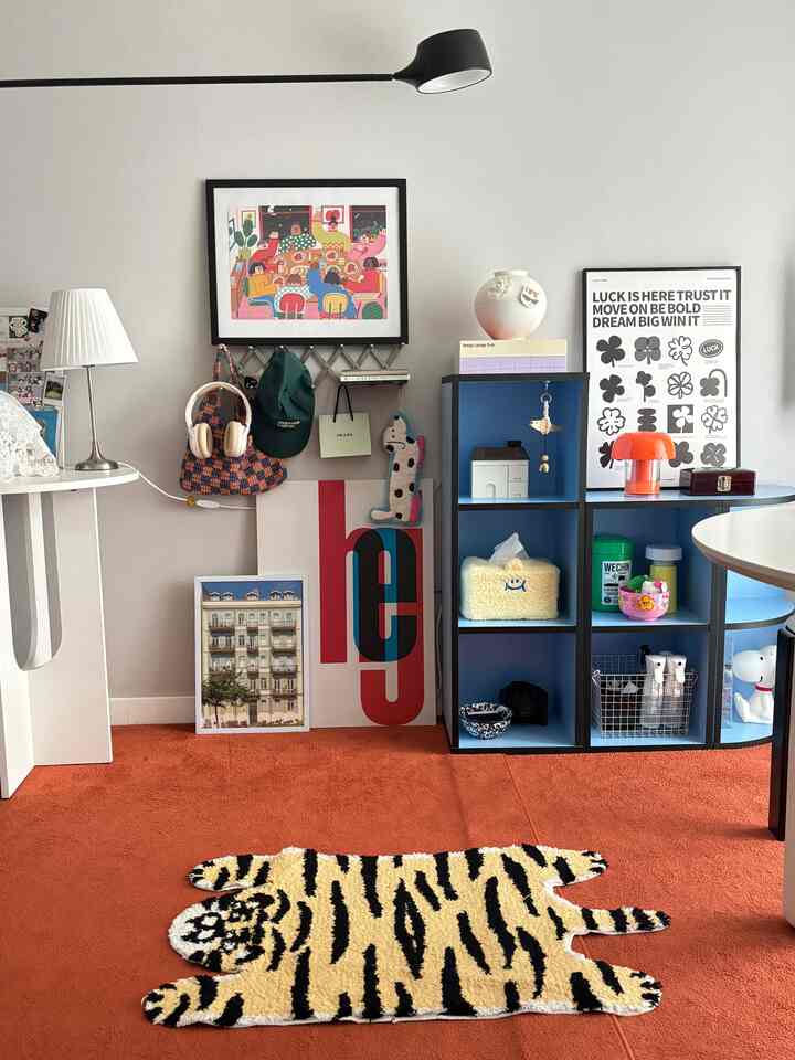 温かみのあるオレンジカーペットと虎の形のラグがある壁デコと棚が配置されたモダンな空間
