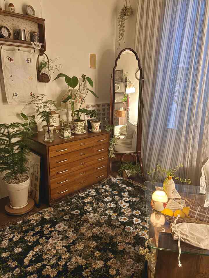 暖かいベージュと木の色調が調和するヴィンテージスタイルのリビング、花柄ラグと複数の鉢植えが配置された居心地の良い空間