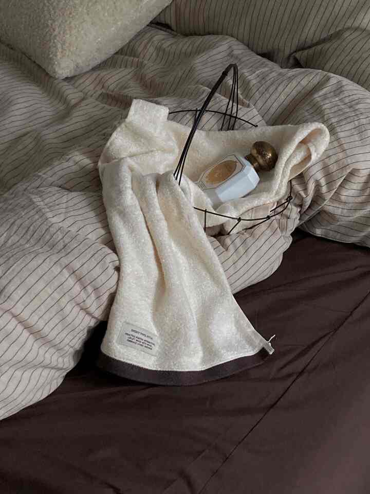 ベージュと茶色のトーンの寝室、ベッドの上にスローとワイヤーバスケットが置かれた温かみのある空間