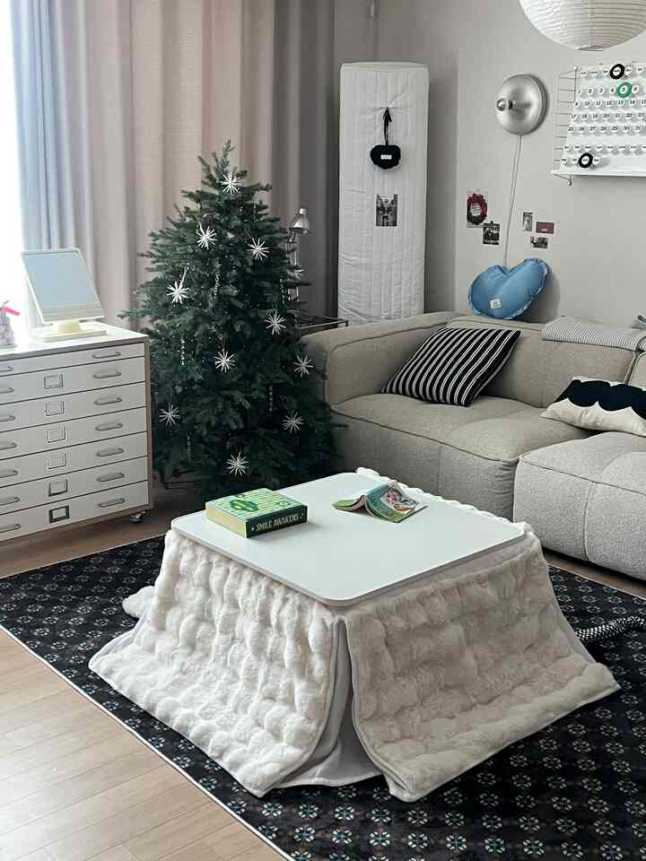 ライトブラウンの床と白いコタツテーブルがあるリビング、ベージュのソファと飾り付けられたクリスマスツリーが配置されたナチュラルモダンな空間