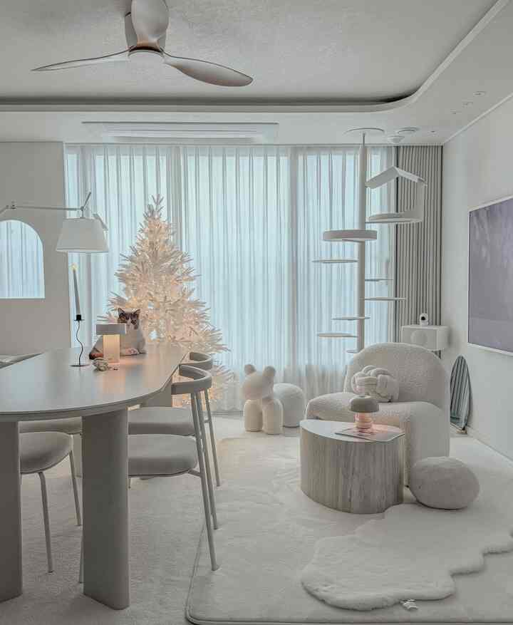 White and beige toned living room featuring a cat tower and white Christmas tree with a modern cozy atmosphere