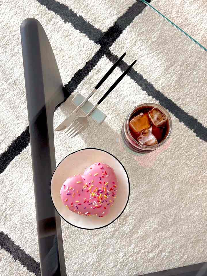 ホワイトとブラックのトーンのテーブルにピンクのドーナツとアイスコーヒーが置かれた雰囲気のあるおうちカフェ