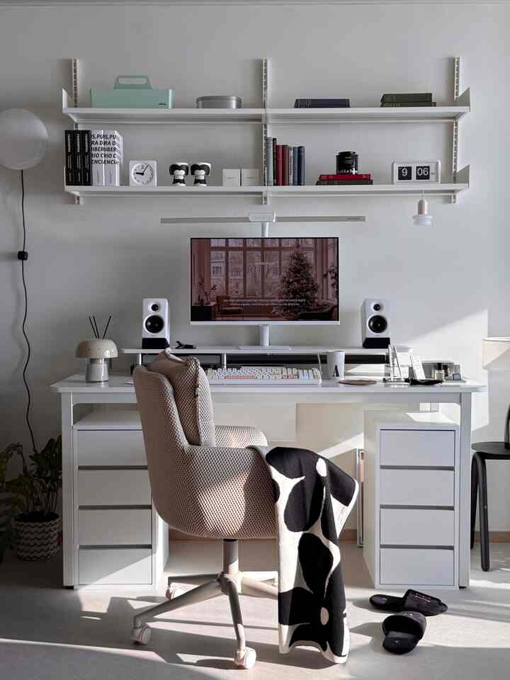 白と黒のトーンのホームオフィス、すっきりしたデスクと質感のあるオフィスチェア、パターン柄のスローが置かれた雰囲気のある空間