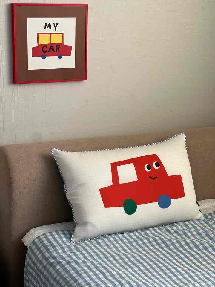 ベージュの色調の子供部屋、かわいい車の絵とキャラクターピローが置かれたベッドのある温かみのある空間