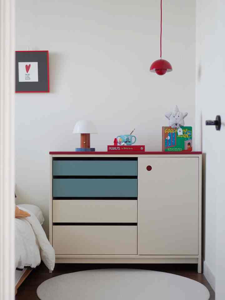 白と赤のアクセントが映える子供部屋、円形ラグとかわいらしい小物が配置された温かみのあるインテリア