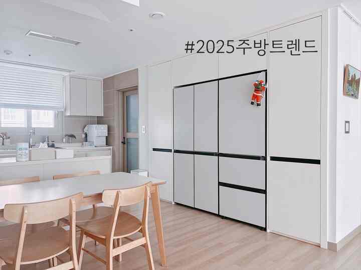 ホワイトと木目調が調和するキッチン空間、冷蔵庫キャビネットとダイニングテーブルが配置されたモダンな雰囲気