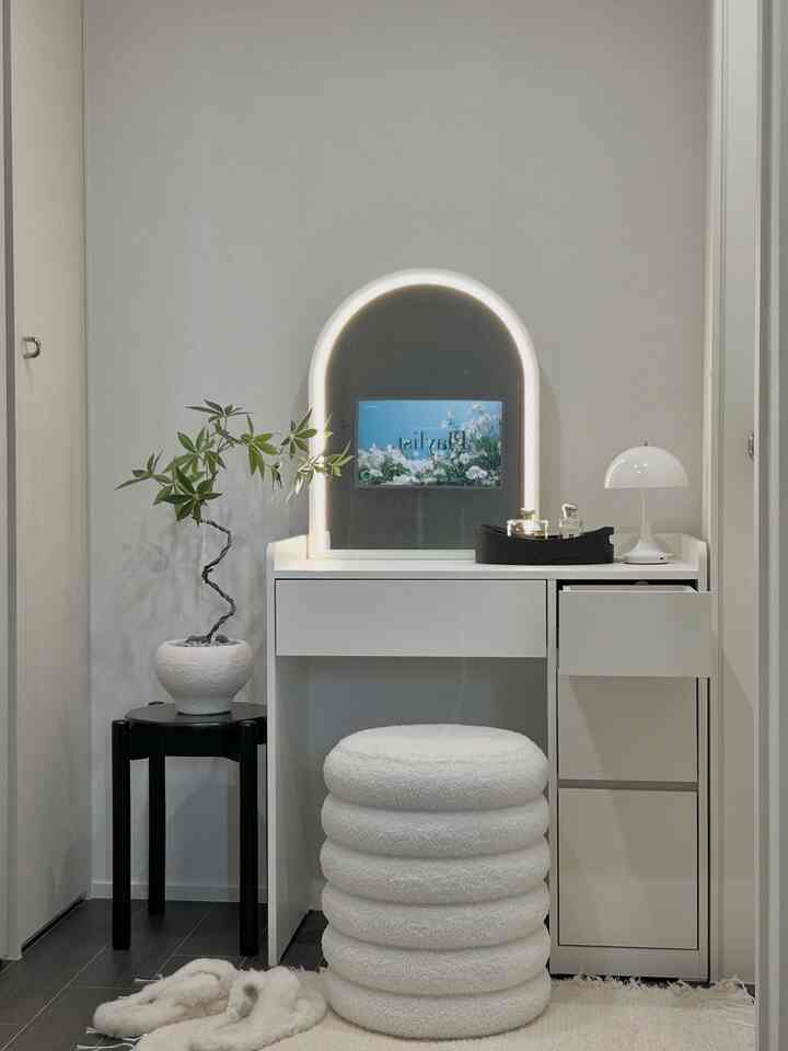 白と黒の調和が取れたシンプルな寝室の化粧台空間、LEDの円形照明とブークレスツールが配置されたモダンなインテリア