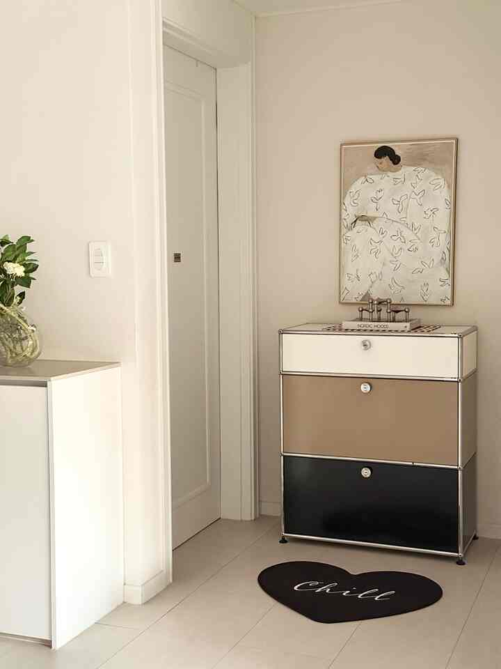 白とベージュの色調の玄関、洗練されたチェストと絵画、ラグが配置された雰囲気のあるモダンな空間