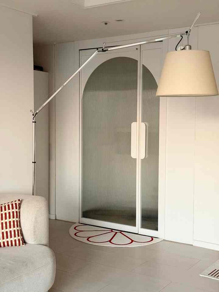 白とナチュラルカラーのリビング、シンプルなソファとフロアランプが配置された雰囲気のある空間