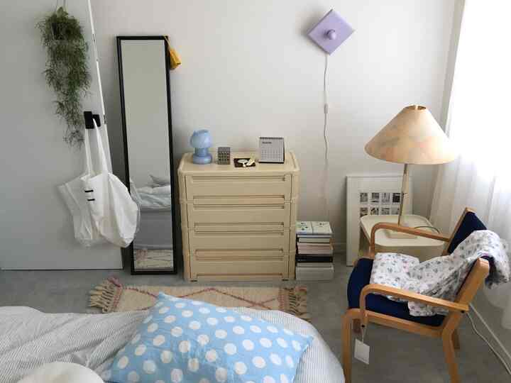 ホワイトとブルーの色調の寝室、ヴィンテージ家具と花柄のブランケットが配置された温かみのあるインテリア