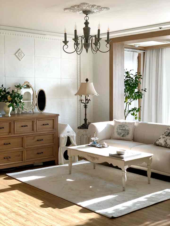 暖かいナチュラルトーンのリビング、クリームホワイトのソファとラグ、木製のチェストとコーヒーテーブルが配置された雰囲気あるインテリア