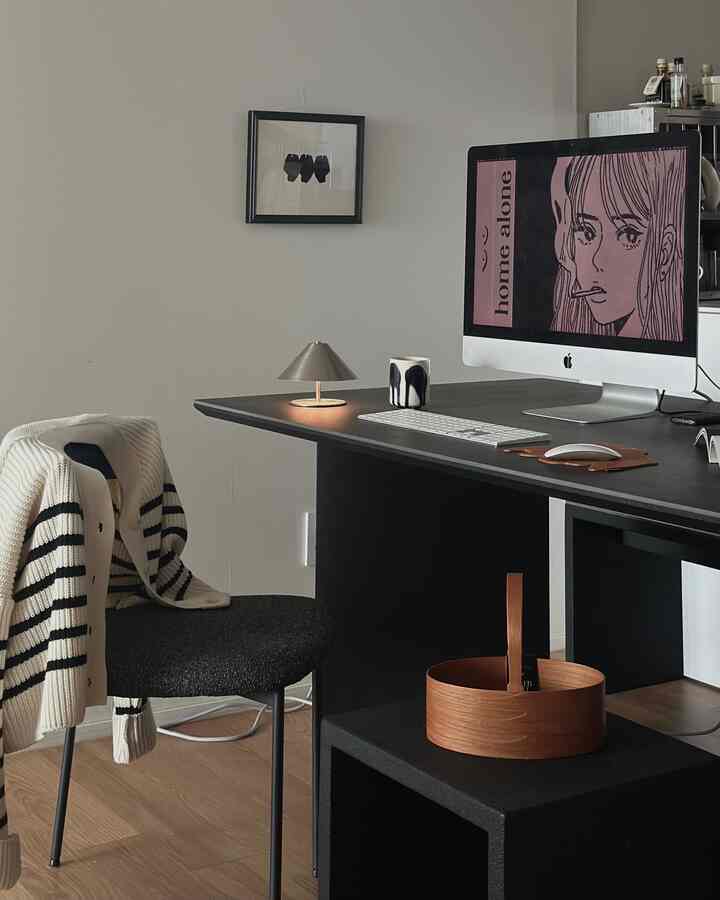 ナチュラルカラーの床とブラックのデスク、オフィスチェア、コンピュータモニターが配置されたシンプルなホームオフィス