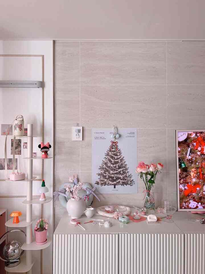 ベージュとホワイトの色調のリビング、クリスマスポスターとピンクの小物が配置された温かみのあるモダンな空間