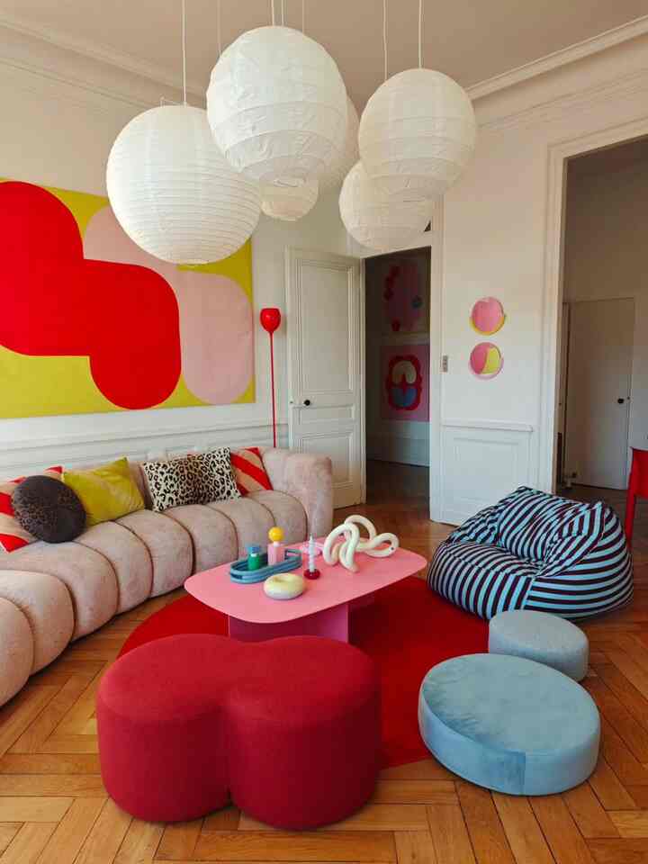 Living room with dominant red and pink tones featuring soft curved sofa and bean bag creating a cozy vibe