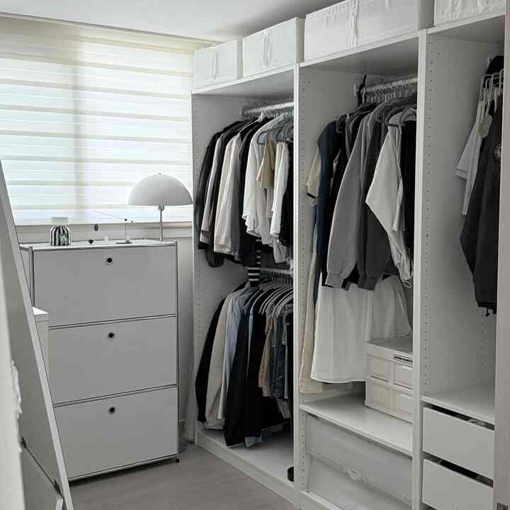 白とナチュラルな色調のウォークインクローゼット、IKEAのPAXとシンプルなチェストが配置された整然とした空間